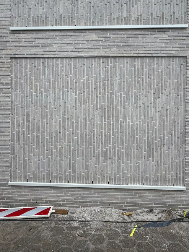 Vlak met verticaal gemetselde lichtgrijze stenen na het voegen in Desselgem