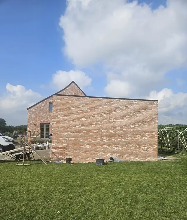 Bakstenen gebouw met nieuw voegwerk, aan een grasveld