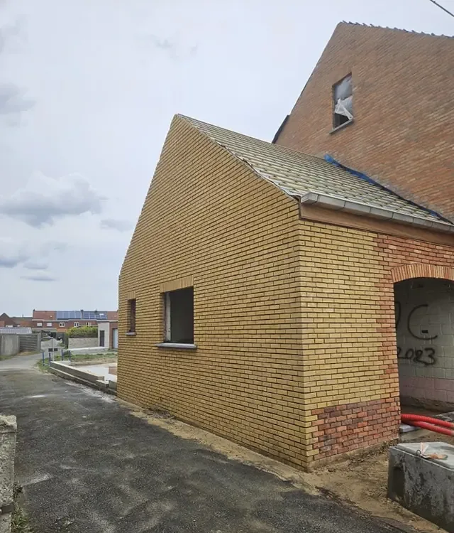 Aanbouw in gele baksteen naast een woning in rode baksteen