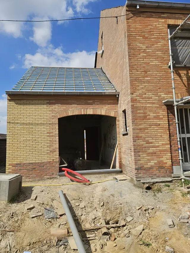 Woning in gele baksteen tijdens de renovatie, met stelling en boogopening