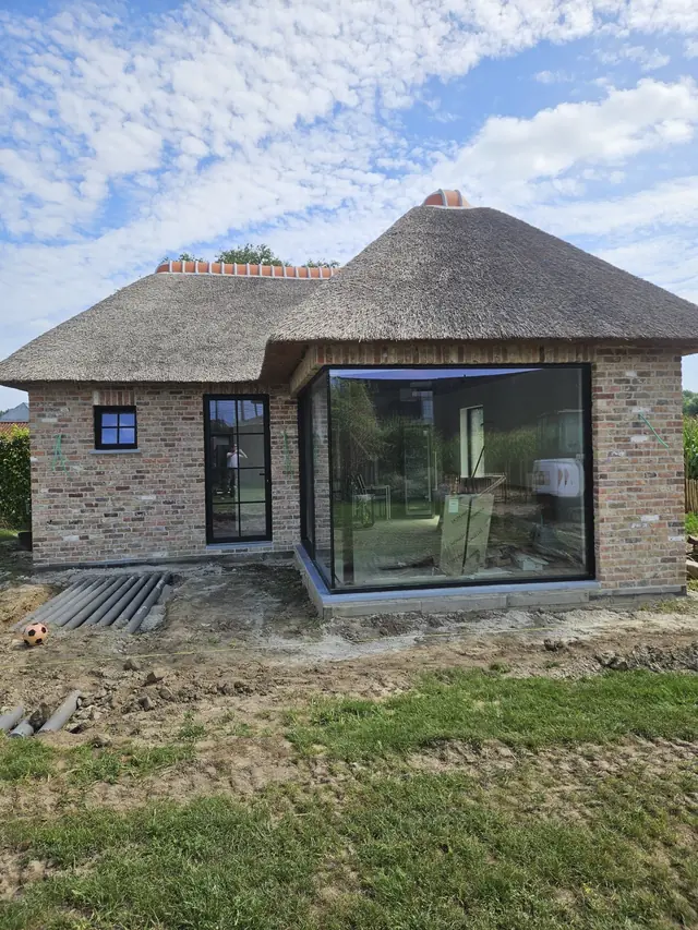Woning met rieten dak en moderne glazen uitbouw