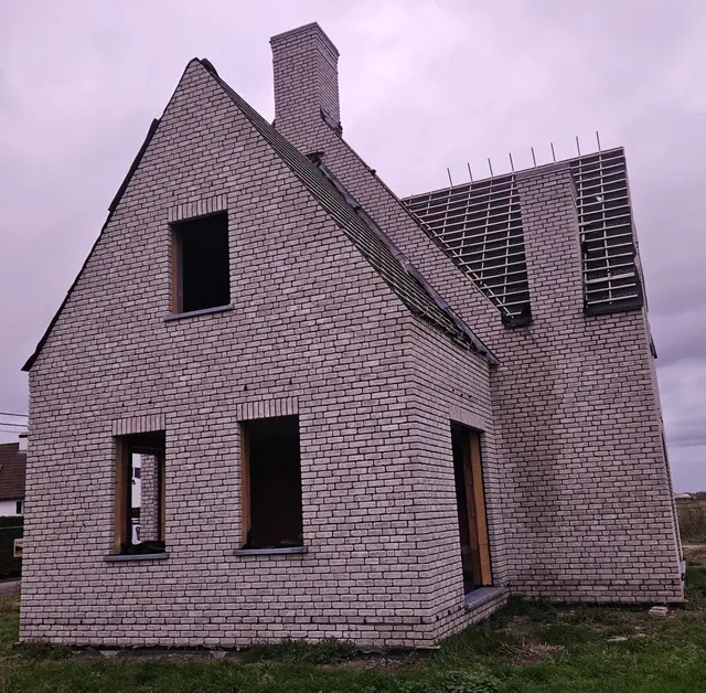 Nieuwbouw in lichte baksteen met puntgevel en schouw