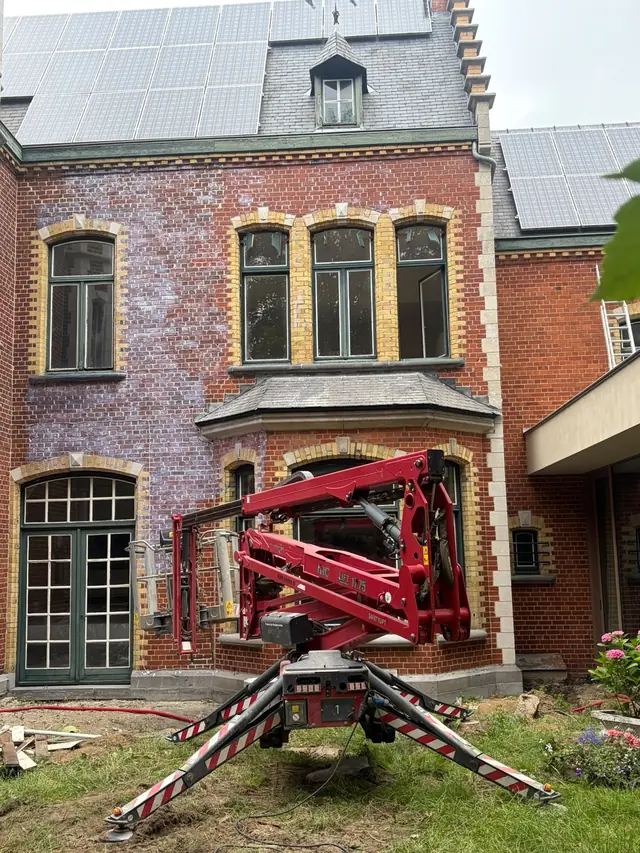 Achtergevel van een herenhuis in Roeselare tijdens de reiniging, deels nog grijs uitgeslagen, met een hoogtewerker