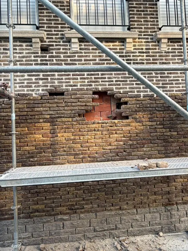 Uitgebroken beschadigde stenen in de gevel, klaar om vervangen te worden