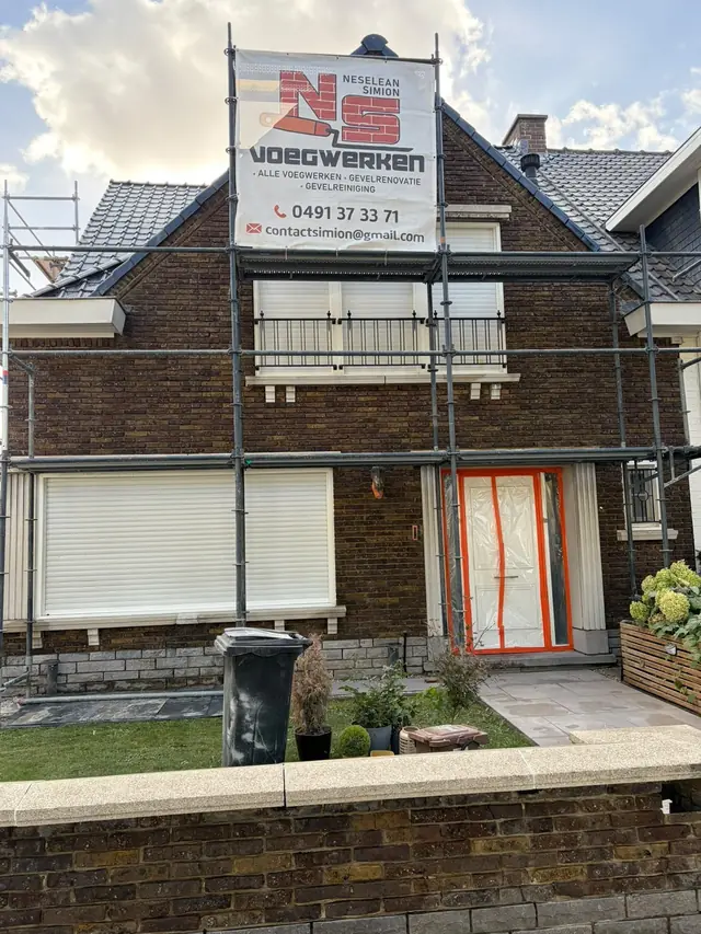 Stelling met het doek van NS Voegwerken tegen de woning in Kortrijk, de voordeur afgeschermd
