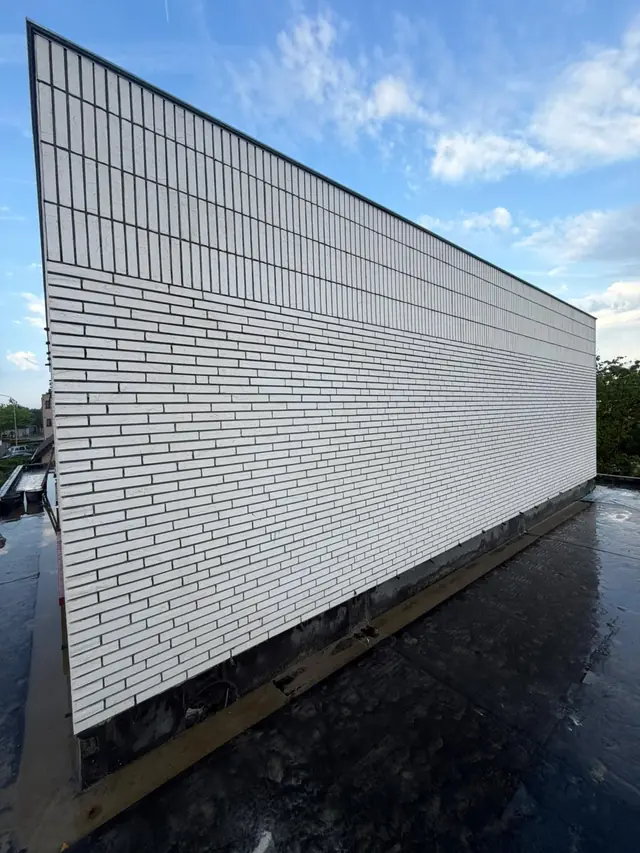 Lange zijgevel in witte langformaatsteen van de nieuwbouw in Kuurne