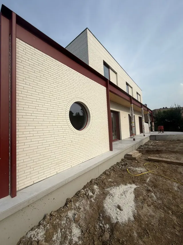 Rond raam in de witte bakstenen gevel van de nieuwbouw in Kuurne