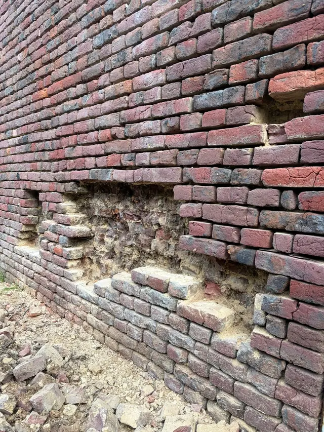 Beschadigd metselwerk met losse stenen in de gevel van de schuur in Lauwe