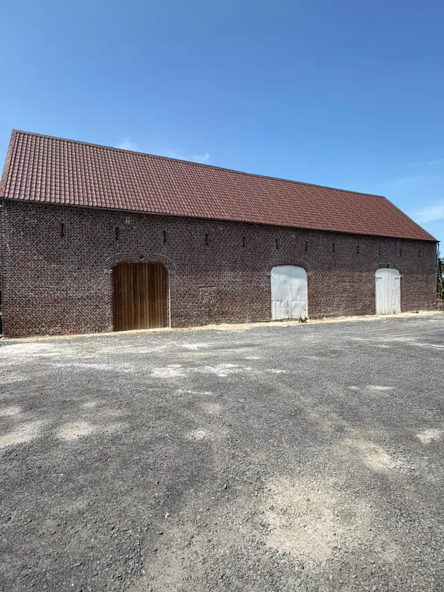 Lange hoeveschuur in oude rode baksteen in Lauwe na het hervoegen