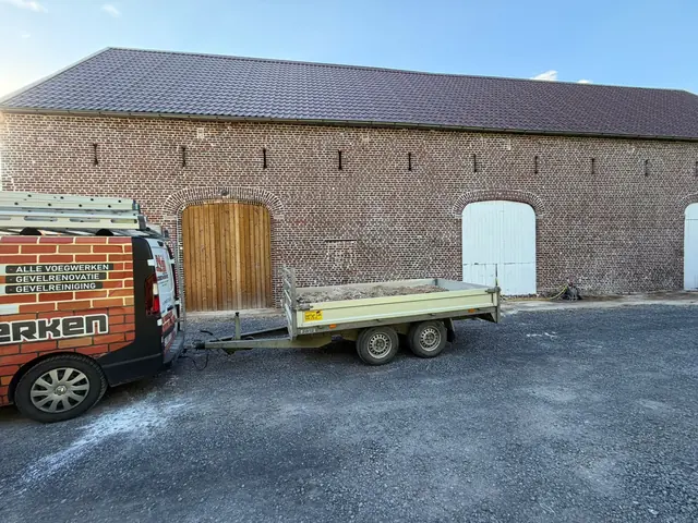 Bestelwagen van NS Voegwerken met aanhangwagen op de werf bij de schuur in Lauwe