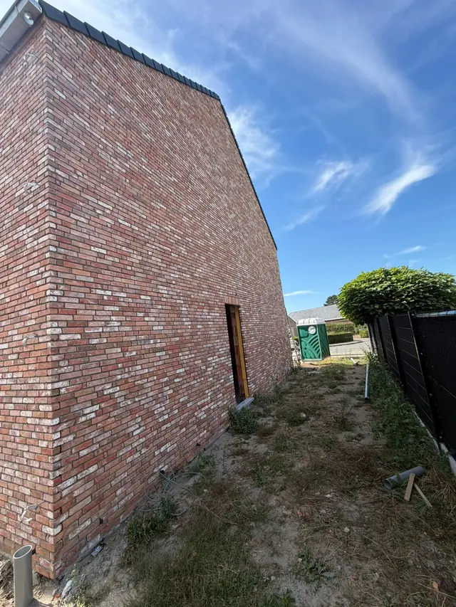 Zijgevel van de nieuwbouw in rode baksteen in Moorslede na het voegen