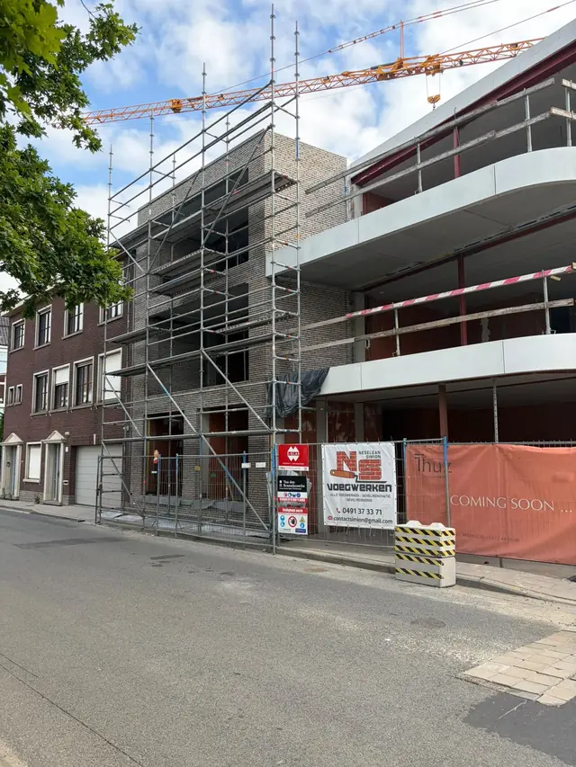 Appartementsgebouw in aanbouw in Desselgem, met stelling en spandoek van NS Voegwerken