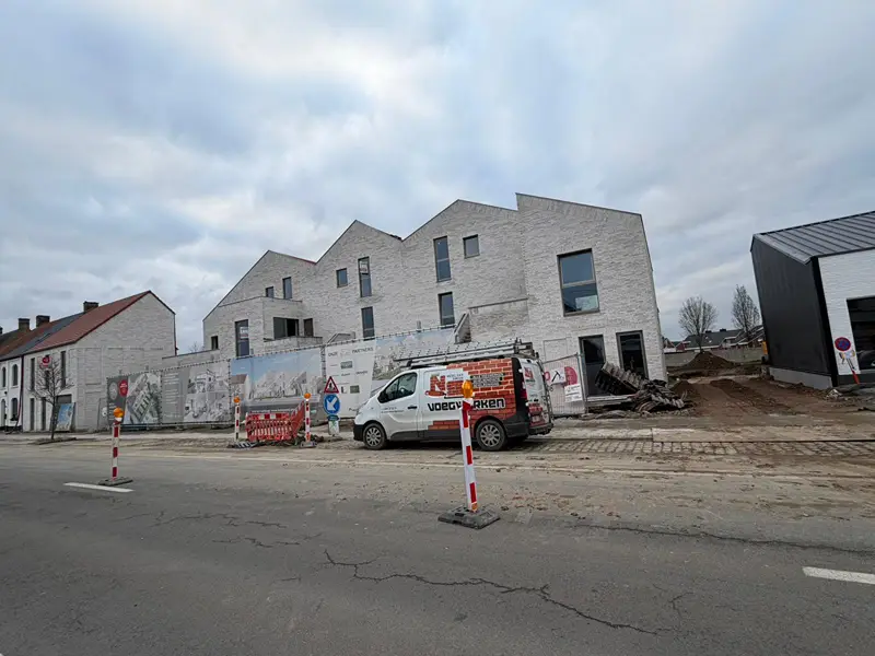 Nieuwbouwproject in lichte baksteen, met de bestelwagen van NS Voegwerken op straat