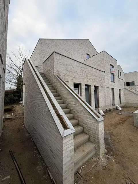 Buitentrap en gevels in lichte baksteen bij een nieuwbouwproject