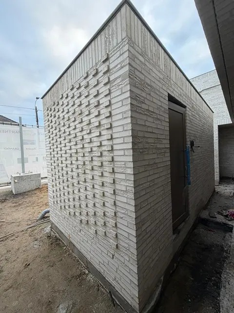 Bijgebouw in lichte baksteen met een patroon van uitstekende stenen
