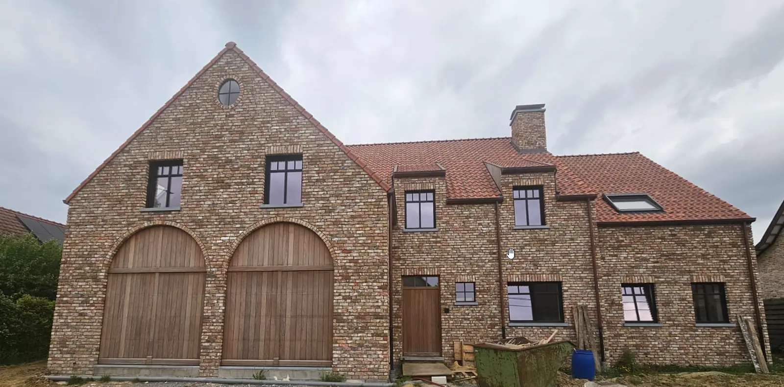 Nieuwbouwwoning met twee houten boogpoorten, het metselwerk nog zonder voegen
