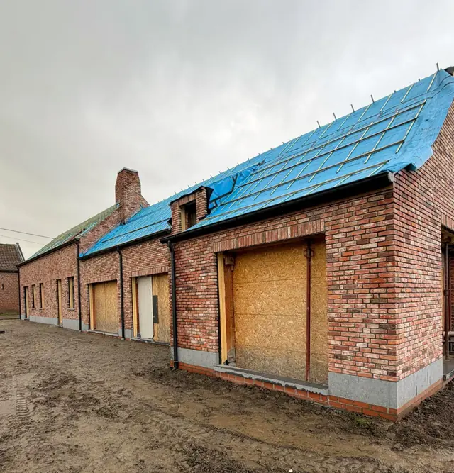 Woning in rode baksteen tijdens de werken, met het dak nog onder folie