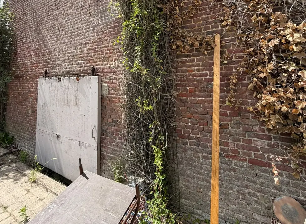 Zijgevel in baksteen in Lauwe, begroeid met klimop, vóór de werken